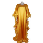 Yellow dress with fringes on a mannequin against a stone wall background