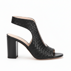 Black woven-texture slingback high-heeled sandals with cutout peep toes, shown being worn and held by a hand against a plain beige background.