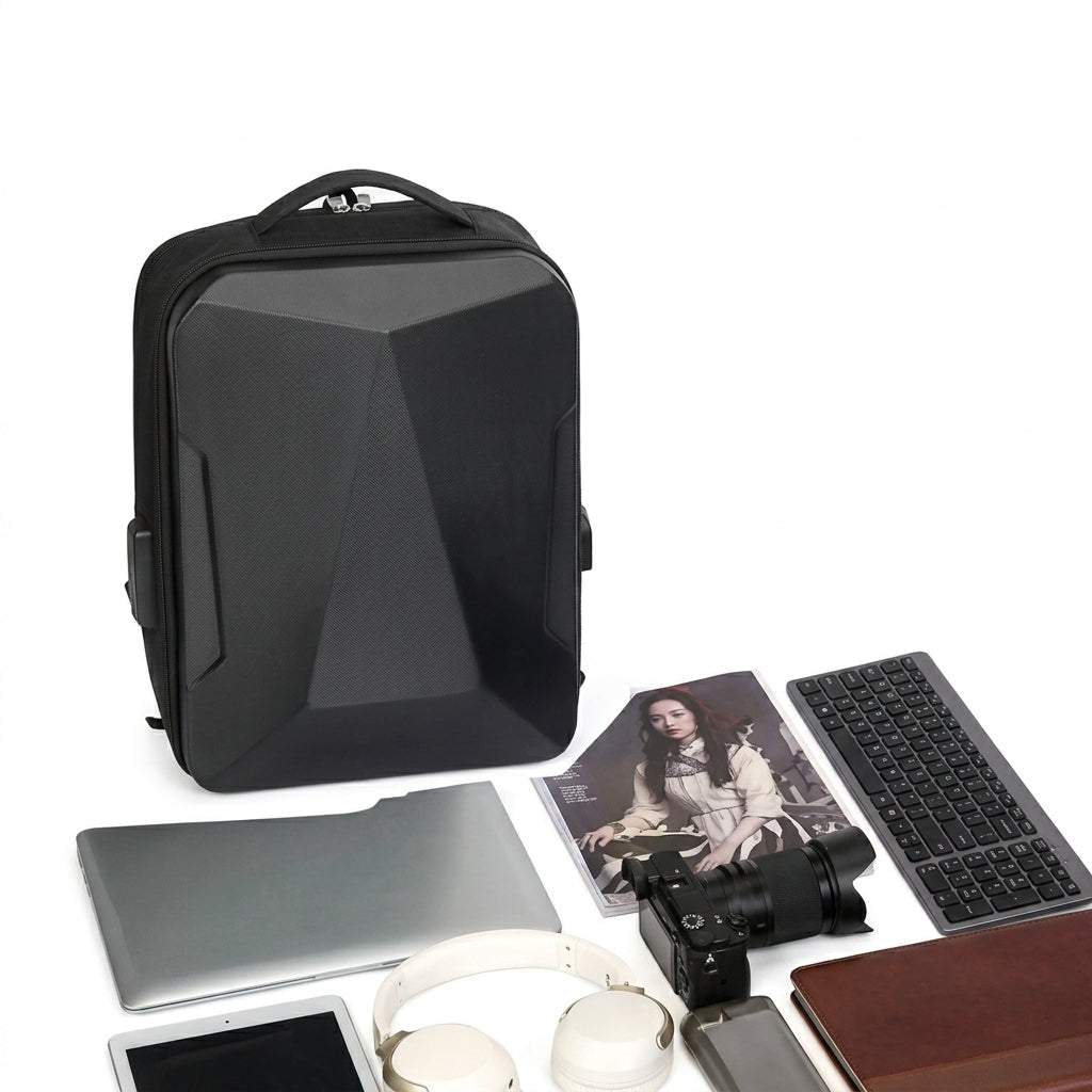 A black geometric laptop backpack displayed on a white background with various tech accessories and a photo print arranged around it.