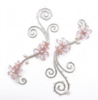 A pair of silver-toned hair claw clips decorated with pink glass flowers and small pearl-like beads, shown on a plain white background.