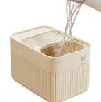 A beige ribbed plastic water dispenser container with a clear lid, shown with water being poured into it from a faucet spout. The brand name 'HONG DA QING' is printed on the side.
