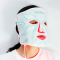 Person wearing a LightAction LED face mask on a plain background