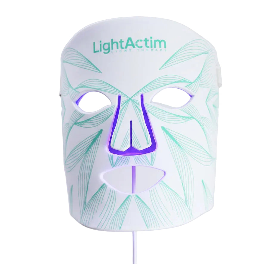 A LightActim facial LED therapy mask on a white background, featuring a white faceplate with light green leaf line patterns and a purple nose cutout.