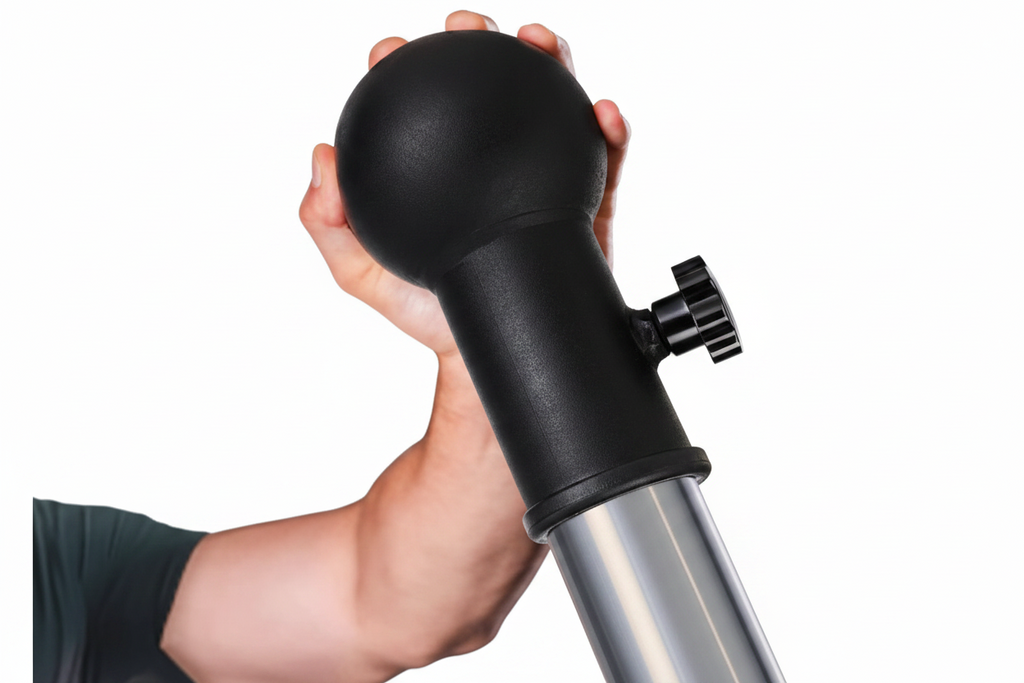 Hand holding a black and silver tool in an indoor setting with equipment in the background