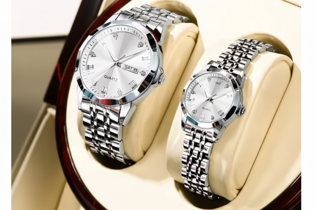 Two silver stainless steel wristwatches with white dials and link bracelets, displayed on beige cushioned stands. A red OLEVS logo badge is visible in the top-left corner.