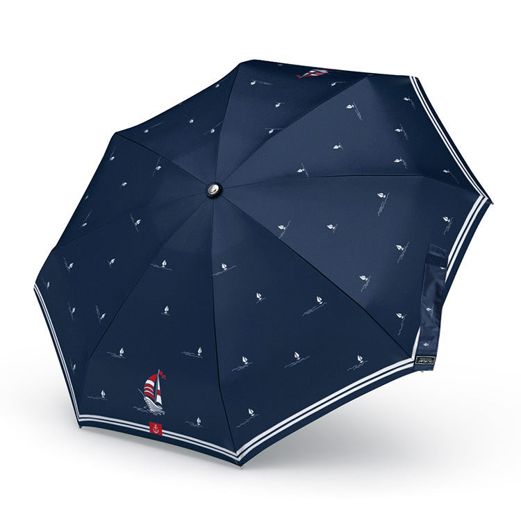 Navy blue umbrella with sailboat pattern on a white background