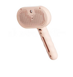 A pet grooming brush with a soft, pale pink handle and head, featuring a textured bristle surface and a side slot, shown against a plain white background.