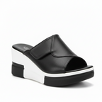Black platform slide sandals with a thick white sole, shown being worn on one foot and held in a hand. The brand name 'Royal Ste.