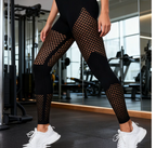 Black athletic leggings with a fishnet pattern on the thighs and calves, worn by a model in a gym setting with white sneakers.