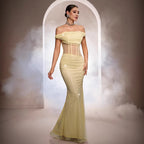 Woman in a yellow evening gown standing in a cloud of smoke with an archway in the background.