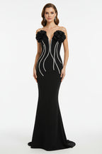 Black evening gown with floral embellishments on a mannequin against a white background