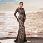 Woman in a black lace evening gown standing on a beach with ocean waves in the background