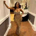 Woman in a sparkling evening gown standing in an elegant room with decorative elements.