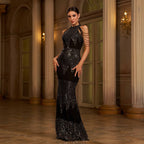 Woman in a black sequin evening gown standing in an elegant interior setting.