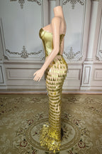 Mannequin wearing a gold dress with a textured skirt in an elegant room.