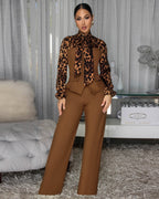 Woman wearing a leopard print top and brown pants in an indoor setting.