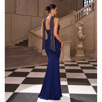 Woman in a blue evening gown with a sequined top standing in an elegant interior setting.