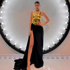 Woman wearing a gold top and black high-slit gown against a circular light fixture background