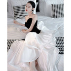 Woman in a black and white dress sitting on a bed with houndstooth pattern.