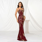 Woman wearing a burgundy floral evening gown against a white curtain background