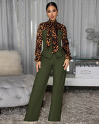 Woman wearing a leopard print top and green pants in an indoor setting.
