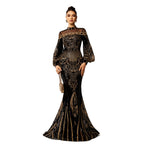 Woman wearing a black and gold evening gown with intricate patterns on a white background