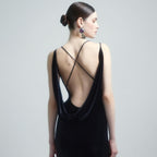 Woman wearing a black dress with thin straps on a plain background