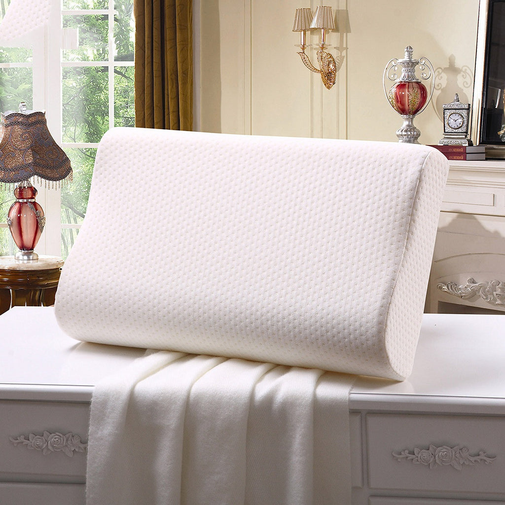 White pillow on a bed in a bedroom setting with decor elements.