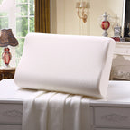 White pillow on a bed in a bedroom setting with decor elements.