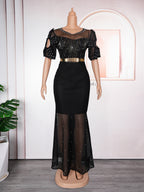 Black dress with sheer sleeves and skirt on a mannequin against a white wall.