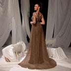 Woman in a brown evening gown with gold detailing standing in front of white draped curtains.