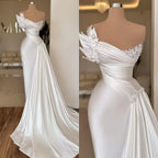 White off-shoulder evening gown on a mannequin with detailed embellishments.
