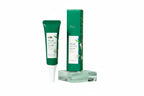A sleek green squeeze tube and box of the Premium Acne Treatment Gel resting on a glass display block next to a sprig of rosemary.