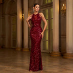 Woman in a red sequin evening gown standing in an elegant indoor setting.