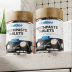 Two jars of OralGos toothpaste tablets on a bathroom counter with text about mint-flavored solid mouthwash tablets.