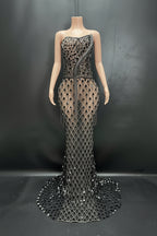 Mannequin wearing a black and silver evening gown with intricate design on a dark background