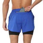 Blue athletic shorts with a black waistband on a gray background